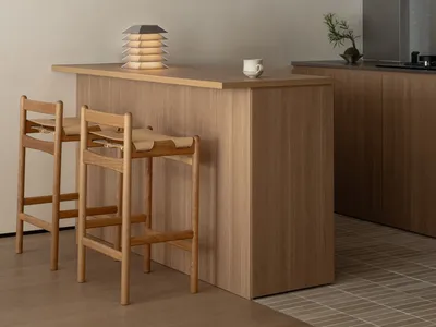 Modern kitchen with wooden cabinets, a wooden island, a sink, a stove, and a refrigerator, with two chairs and bright, well-lit atmosphere