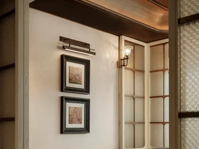 A dimly lit dining area with a wooden table and chairs, surrounded by a predominantly white room