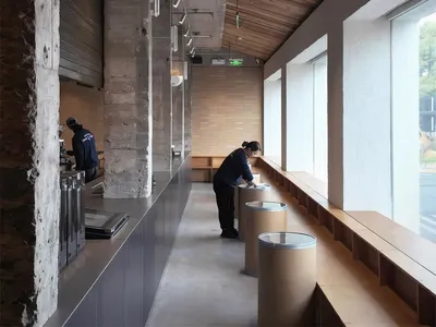 Modern bathroom with a wooden counter, sink, and bench, filled with natural light from the windows