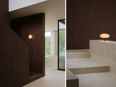 Dimly lit bathroom living space with a wooden floor, stone wall, and a large window, featuring a staircase and a sink