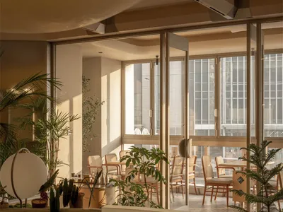 Spacious dining room with multiple chairs and tables, natural light, and a modern aesthetic