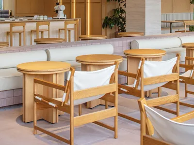 A modern restaurant interior with brown and white tables, brown chairs, and a warm atmosphere created by well-placed lighting