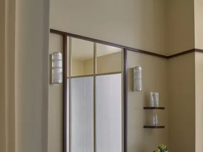 Bathroom with a wooden vanity, sink, and vase with flowers, featuring a warm and inviting atmosphere with wood and glass materials
