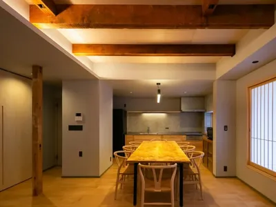 一間現代廚房和餐廳區域，配有木桌椅和多款家電，透過自然光照明