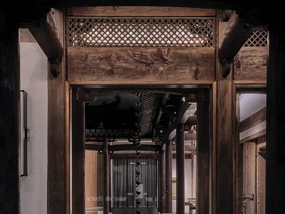 A dimly lit bathroom with a wooden doorway, a bathtub, and an open doorway inviting the viewer in