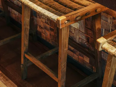 A wooden dining table and chairs in a restaurant setting, surrounded by a bench, creating a warm and inviting atmosphere for a relaxed dining experience