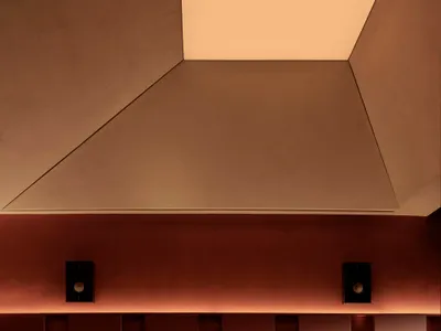 Cozy modern dining space with brown tables, black chairs, and a red brick pattern on the walls, lit by dim lighting