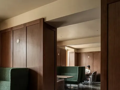 Cozy dining room with a wooden floor, brown color scheme, a dining table, and a couch, featuring a mix of modern and traditional elements