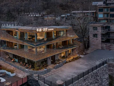 A large modern building with a unique design featuring a combination of stone and wood elements, well-lit with natural light from the windows