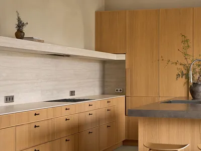 Modern kitchen with wooden cabinets, a sink, stove, and refrigerator, with natural light and two chairs