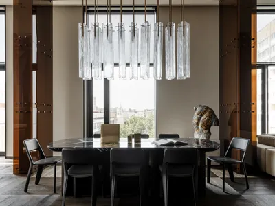 Modern dining space with a glass chandelier, wooden chairs, and a black and white color scheme, set against a window background