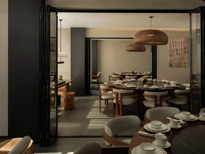 A modern restaurant with a large dining area filled with chairs and tables, set with white tableware, creating a cozy atmosphere