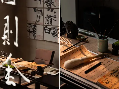 A cluttered room with a mix of furniture, decorations, and artwork, featuring a dining table, chair, couch, books, Asian art, and a painting and sculpture