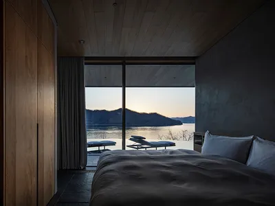 A well-lit bedroom with a large bed, white comforter, and natural light from a large window