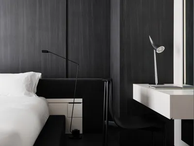 A dimly lit black and white bedroom with a bed, desk, and chair, creating a cozy and intimate atmosphere