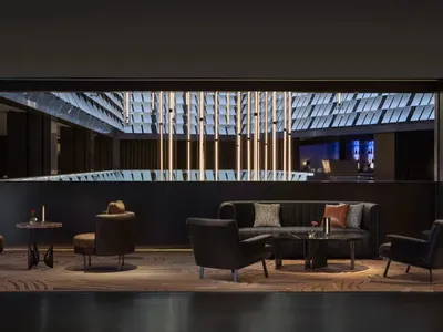 A well-lit living room with a black couch, a chair, and a dining table, surrounded by various decorative items
