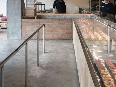 A modern restaurant with a brick wall, black and white color scheme, and a man working behind the counter in a well-lit space