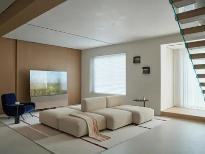 A well-lit living room with a large couch, flat screen TV, rug, chair, and two lamps, creating a comfortable and inviting atmosphere