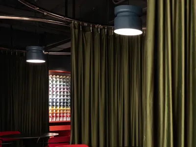 A cozy dining area with a black table surrounded by red chairs and a elegant curtain in the background