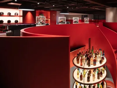 一間溫馨空間內有螺旋梯、酒吧與餐桌，擺滿各種形狀大小的酒瓶，營造視覺吸引的氛圍