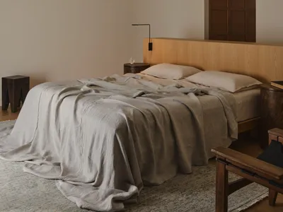 Cozy bedroom with a bed, chair, and lamp, featuring a wooden headboard and a white color scheme, with dim lighting