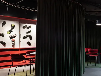 A cozy dining-living space with a green curtain, a dining table, and pairs of shoes displayed on the walls
