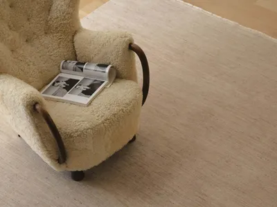 A well-lit living room with a chair covered in white fur and a magazine on it, creating a comfortable and inviting atmosphere