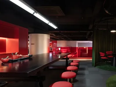溫馨現代餐廳，設有長吧台、紅色點綴與柔和燈光，鼓勵社交互動