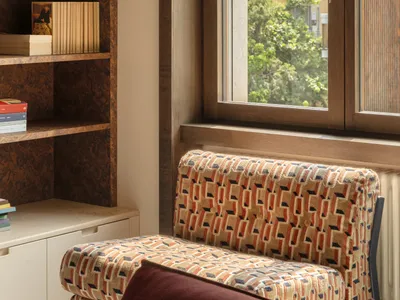 Cozy living room with a wooden bookshelf, a large window, and a comfortable couch in a modern space with natural light