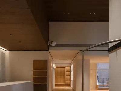 Open living space with a black couch, wooden elements, and a kitchen counter, featuring a warm and cozy atmosphere with dim lighting