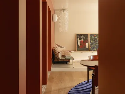 Warm and inviting room with a wooden floor, red walls, a dining table, couch, and lamp, creating a comfortable space for relaxation and socializing