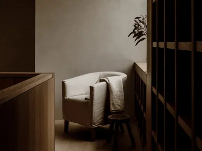 A cozy living space with a wooden floor, a white chair, and a potted plant adding a touch of greenery