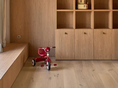 A dimly lit room with wooden walls and floor, featuring a wooden bookshelf with a toy house and a red toy car, creating a cozy and intimate atmosphere