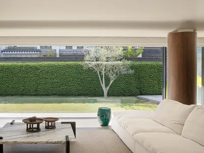 A cozy living room with a white couch, coffee table, and chair, surrounded by natural light from a large window