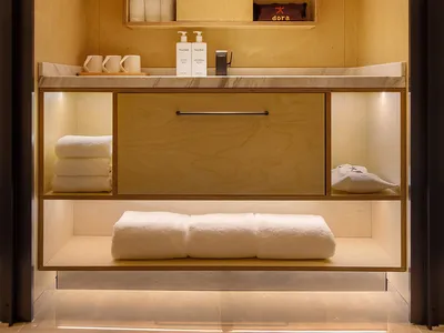A cozy bathroom with a wooden sink, mirror, and nearby bed, creating a warm and inviting atmosphere