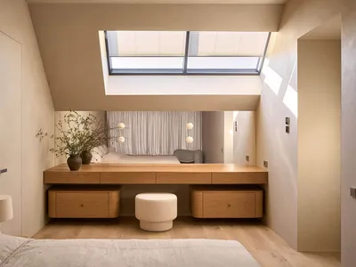 Cozy bedroom with a bed, chair, and dining table, featuring wood and glass materials, with natural light streaming in through the large window