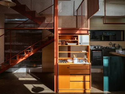 Modern kitchen with wooden cabinets, a metal staircase, and natural light from windows