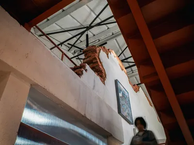 一位女性走上樓梯，位於一座部分完工建築物前，建築物有磚牆，背景有吊車，自然光線下