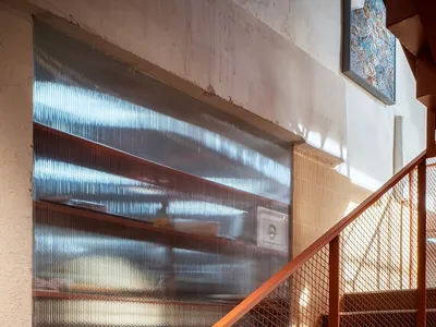 A modern staircase in a kitchen area with a metal railing and brown color scheme, surrounded by a pantry and natural light