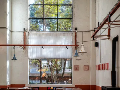 一間溫馨餐廳，擁有大片窗戶、木質家具與餐桌，自然光線與暖陽照耀