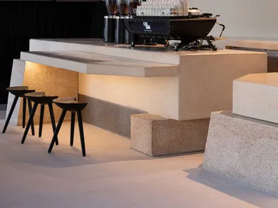 A dimly lit bar with a marble counter and a black coffee machine, creating a cozy and inviting atmosphere