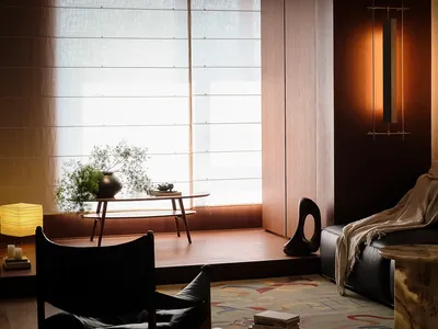 Comfortable living space with a black couch, a chair, and a dining table, set against a hardwood floor and a window, with soft natural light