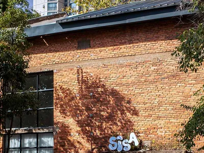 A casual restaurant with a brick facade, people walking in and out, and a chair in the foreground