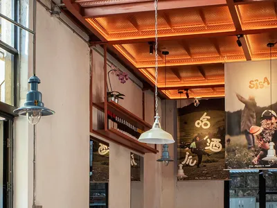 A dimly lit restaurant interior with a table and chairs, surrounded by wood and metal furniture, decorative plants, and vases, creating a warm and inviting atmosphere
