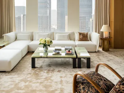 Cozy living space with white furniture, a large window, and natural light, featuring a couch, coffee table, and chair