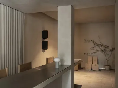 A modern restaurant dining area with a metal counter and a dining table surrounded by chairs, featuring soft and inviting lighting