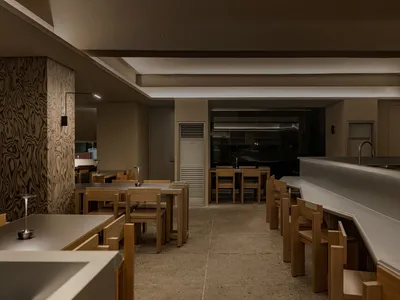Cozy modern restaurant interior with a large dining table, kitchen appliances, and comfortable seating