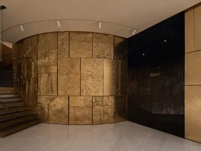 Luxurious living space with a gold-colored accent wall, a staircase, and natural light from windows