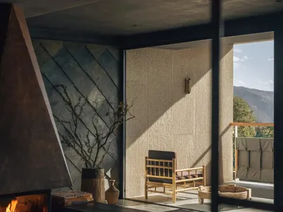 Cozy living room with a fireplace, a couch, and a chair, featuring a mix of natural and artificial lighting, and a modern functional style
