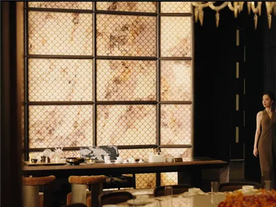 一位女性站在餐桌旁，桌上有椅子與餐具，位於優雅而溫馨的餐廳風格用餐空間